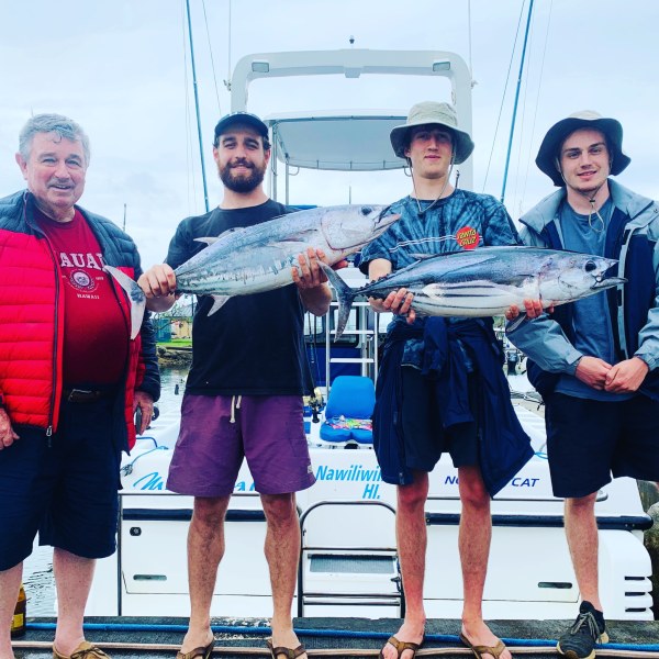 a group of people standing next to a person holding a fish