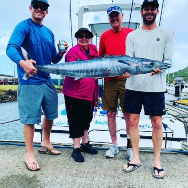 a group of people standing next to a person holding a fish
