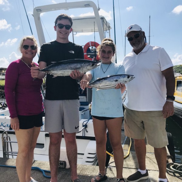 a group of people standing next to a person holding a fish