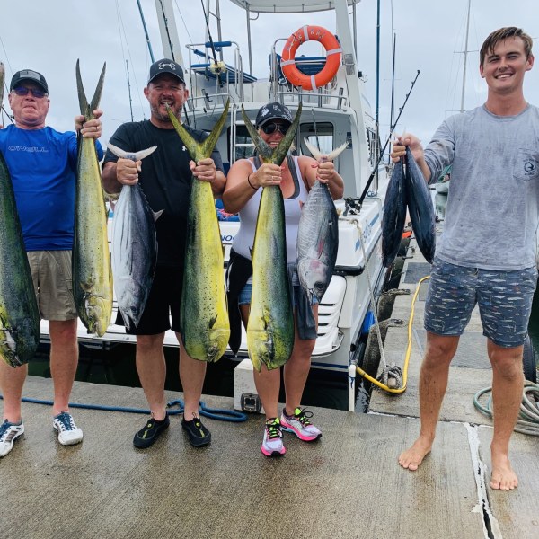 a group of people standing next to a man holding a fish