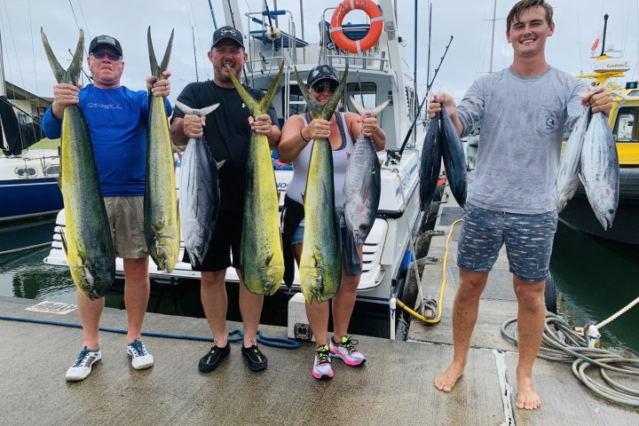 a group of people standing next to a man holding a fish