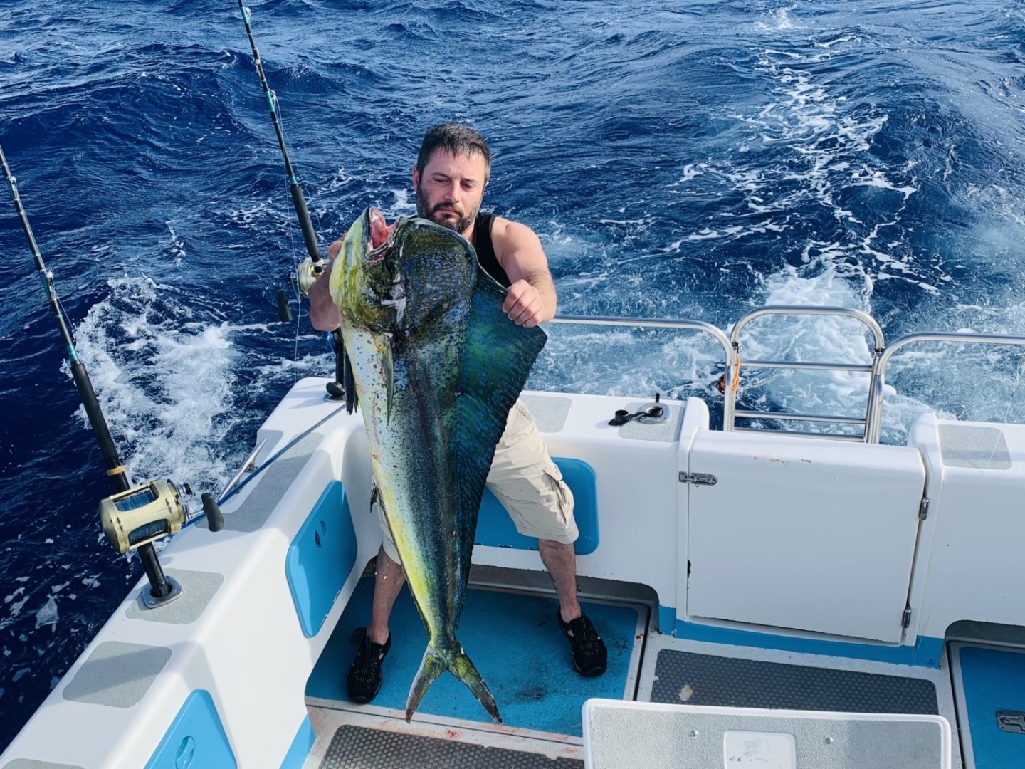 a man holding a fish on a boat in the water