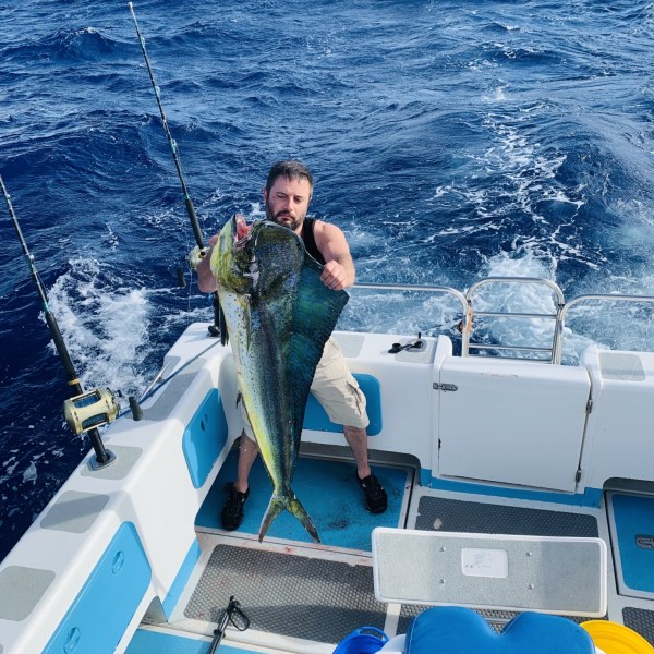 a man holding a fish on a boat in the water