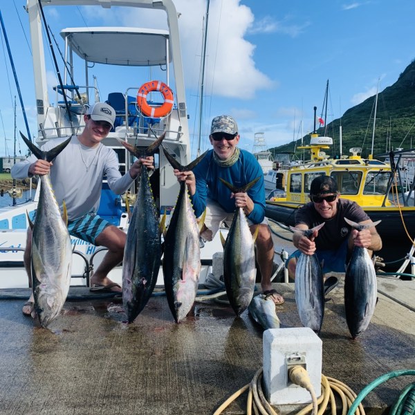 a group of people standing next to a fish on a boat